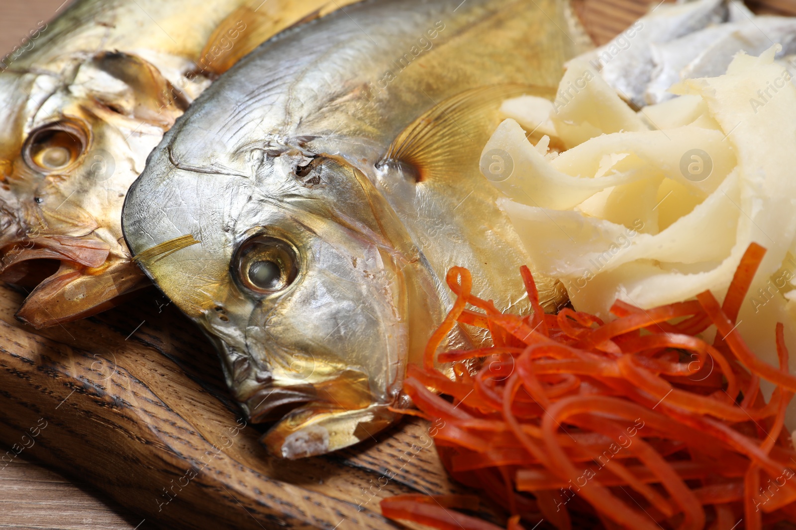 Photo of Many different dried fish snacks on wooden table, closeup