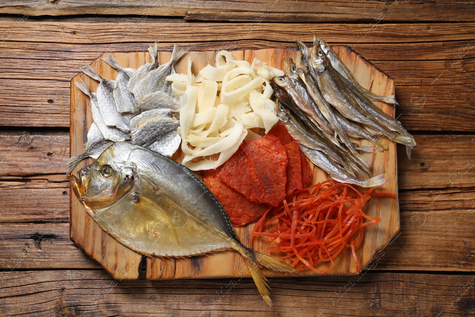 Photo of Many different dried fish snacks on wooden table, top view