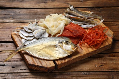 Many different dried fish snacks on wooden table