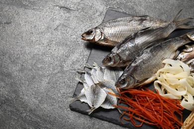 Many different dried fish snacks on grey table. Space for text