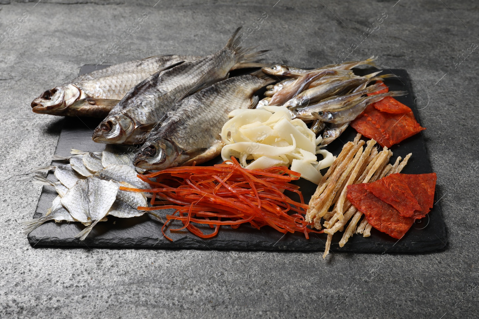 Photo of Many different dried fish snacks on grey table