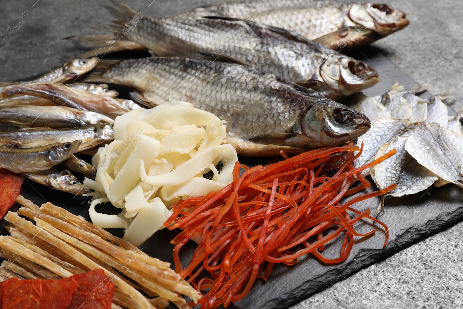 Photo of Many different dried fish snacks on grey table, closeup