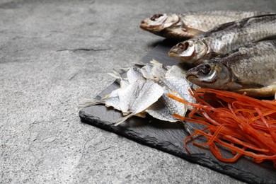 Many different dried fish snacks on grey table, closeup. Space for text