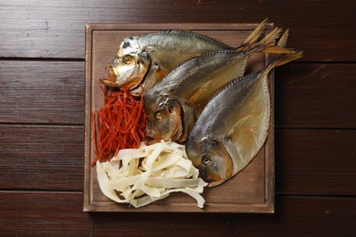 Many different dried fish snacks on wooden table, top view