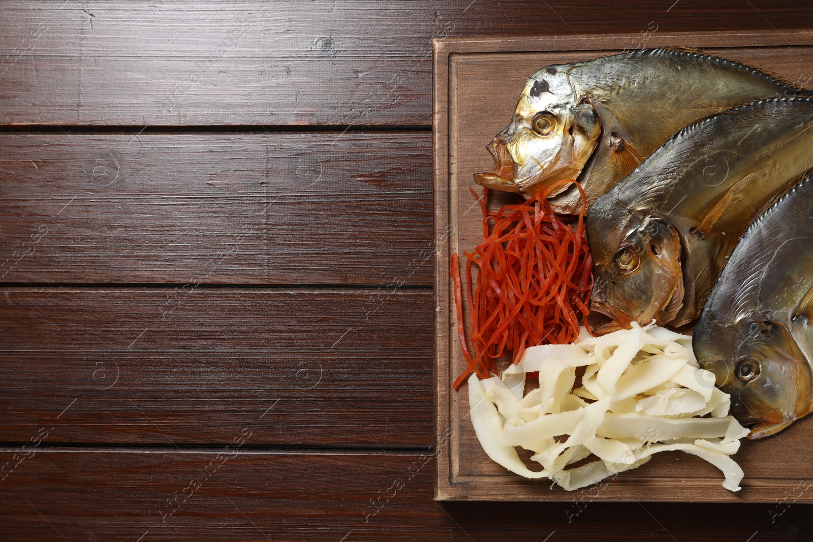 Photo of Many different dried fish snacks on wooden table, top view. Space for text