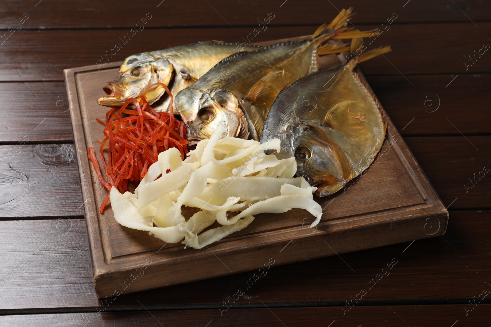 Photo of Many different dried fish snacks on wooden table, closeup