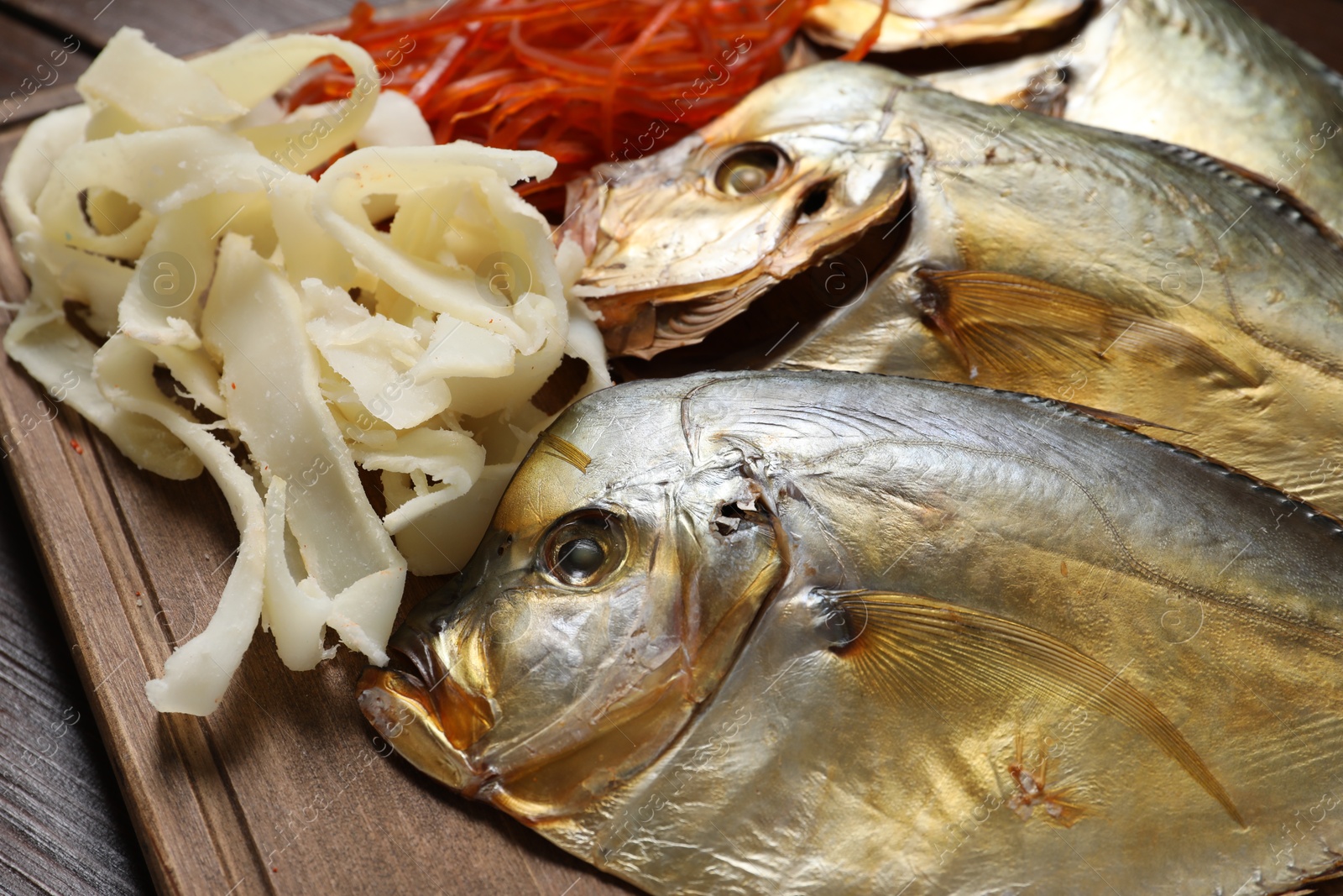 Photo of Many different dried fish snacks on wooden table, closeup