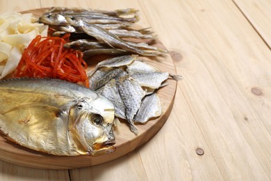 Photo of Many different dried fish snacks on wooden table, closeup. Space for text