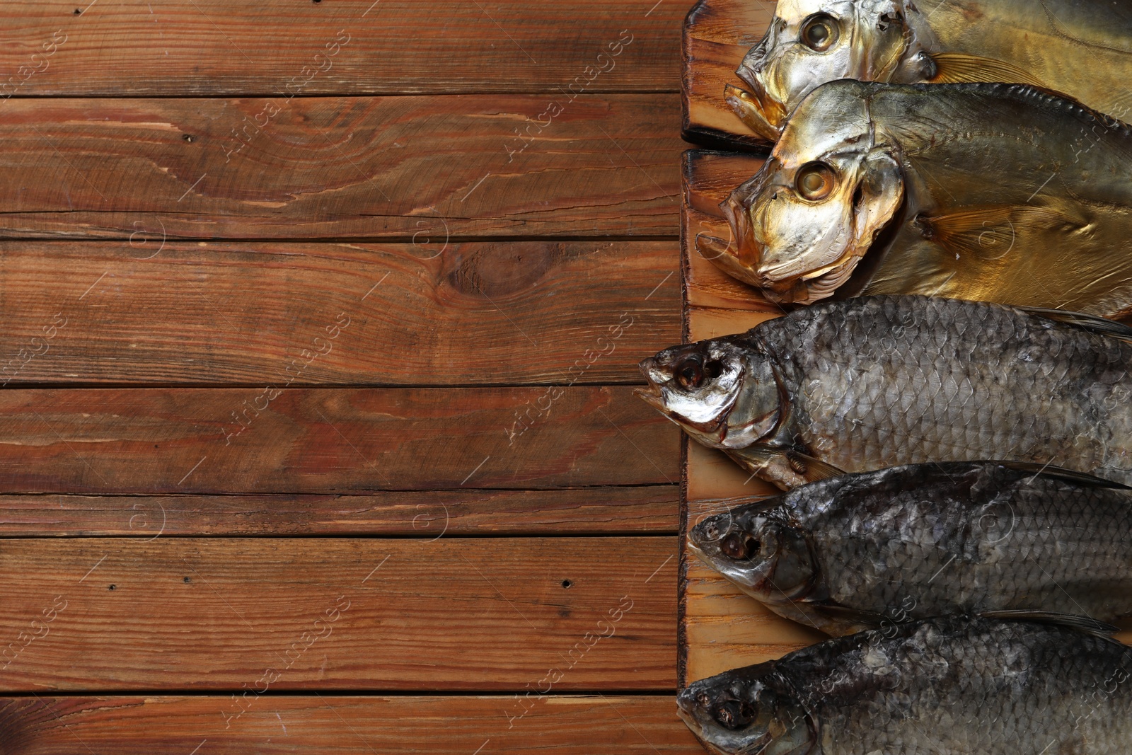 Photo of Many different dried fish on wooden table, closeup. Space for text