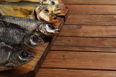 Photo of Many different dried fish on wooden table, closeup. Space for text