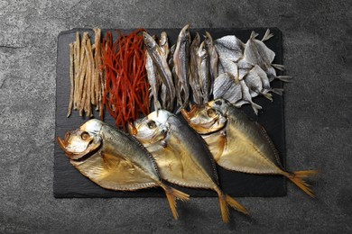 Many different dried fish snacks on grey table, top view