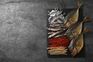 Many different dried fish snacks on grey table, top view. Space for text