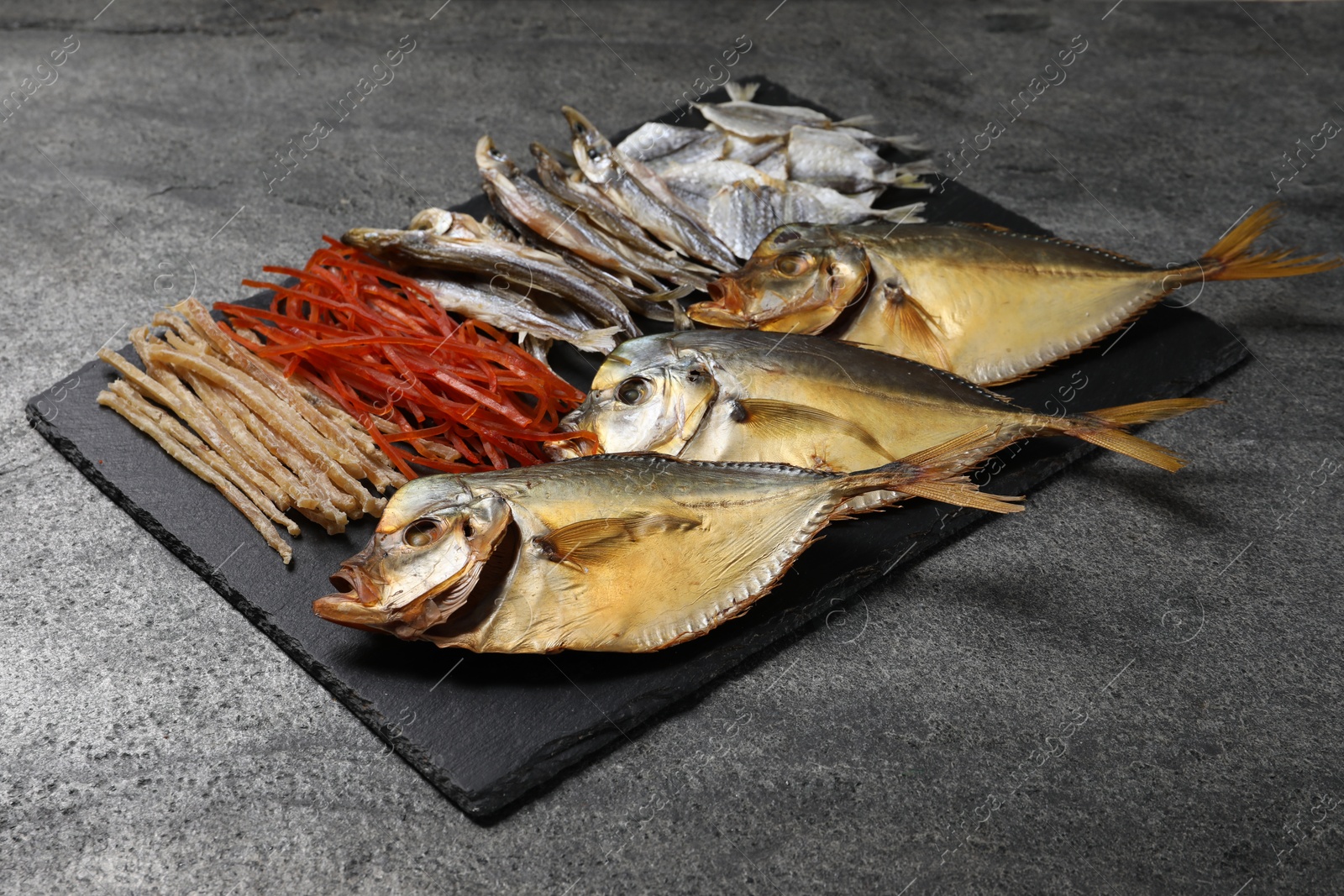 Photo of Many different dried fish snacks on grey table