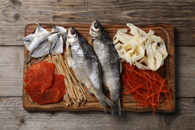 Photo of Many different dried fish snacks on wooden table, top view