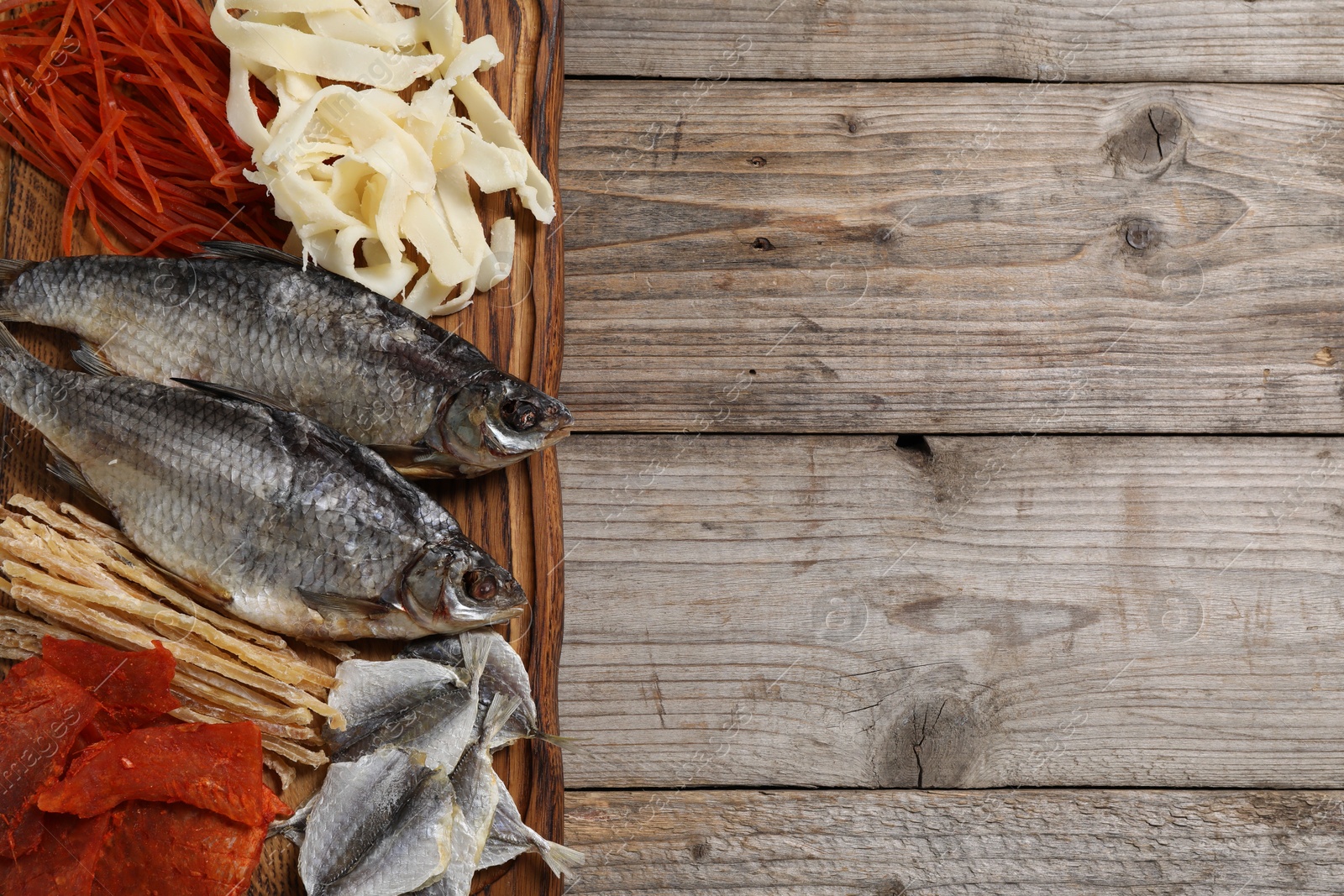 Photo of Many different dried fish snacks on wooden table, top view. Space for text