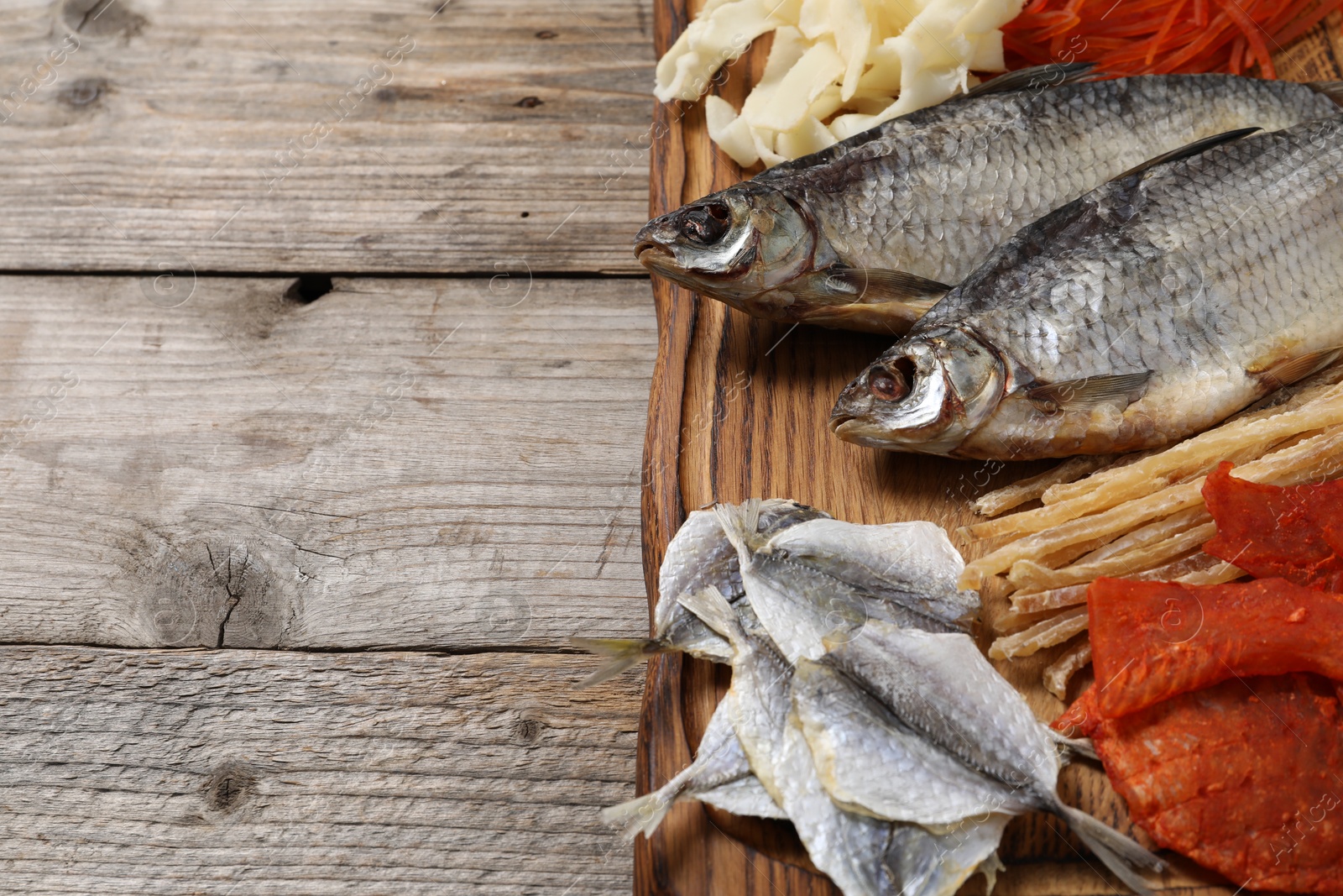 Photo of Many different dried fish snacks on wooden table, closeup. Space for text