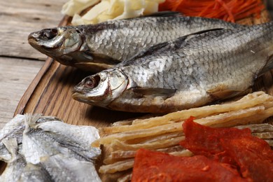 Many different dried fish snacks on wooden table, closeup