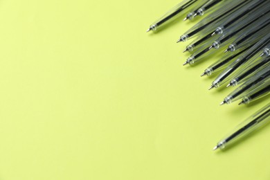 Photo of Many ballpoint pens on light green background, above view. Space for text