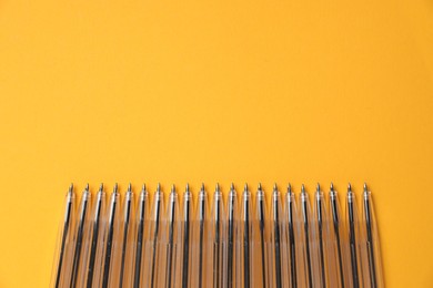 Photo of Many ballpoint pens on orange background, flat lay. Space for text