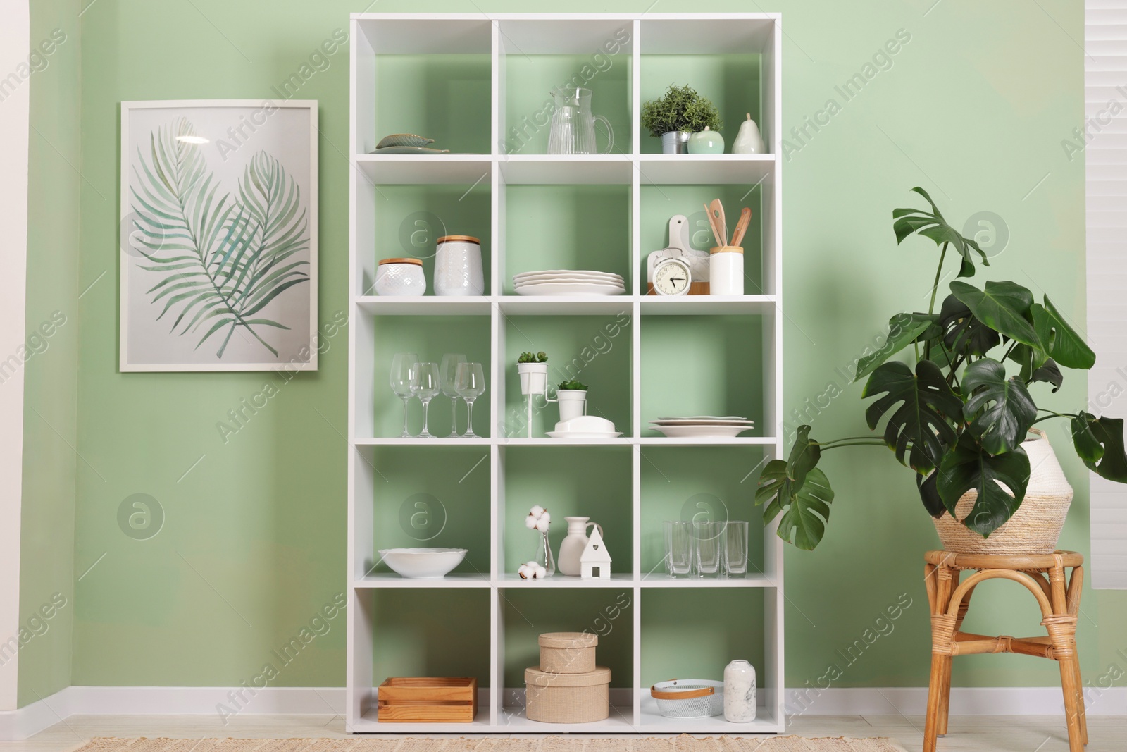 Photo of Shelving unit with dishware near olive wall indoors