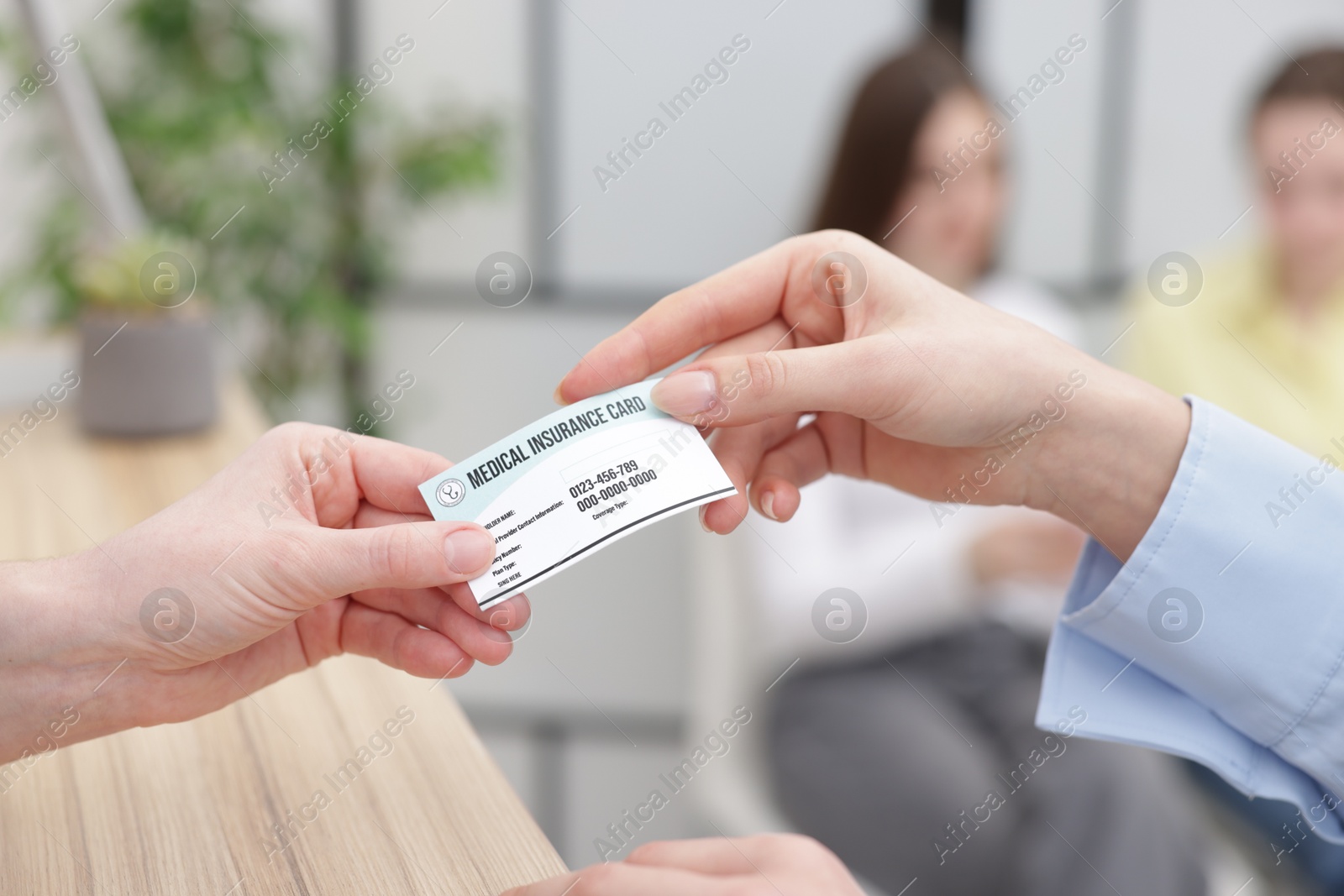 Photo of Patient giving medical insurance card to receptionist at counter in clinic, closeup