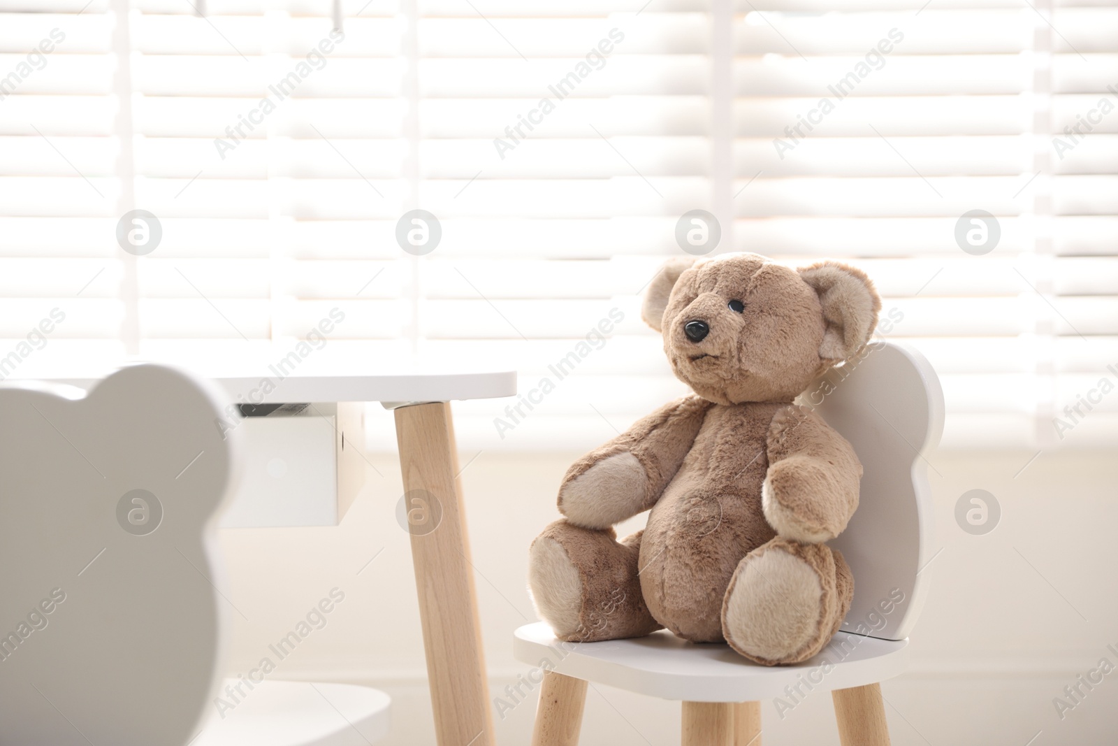 Photo of Cute teddy bear on chair in child's room. Space for text