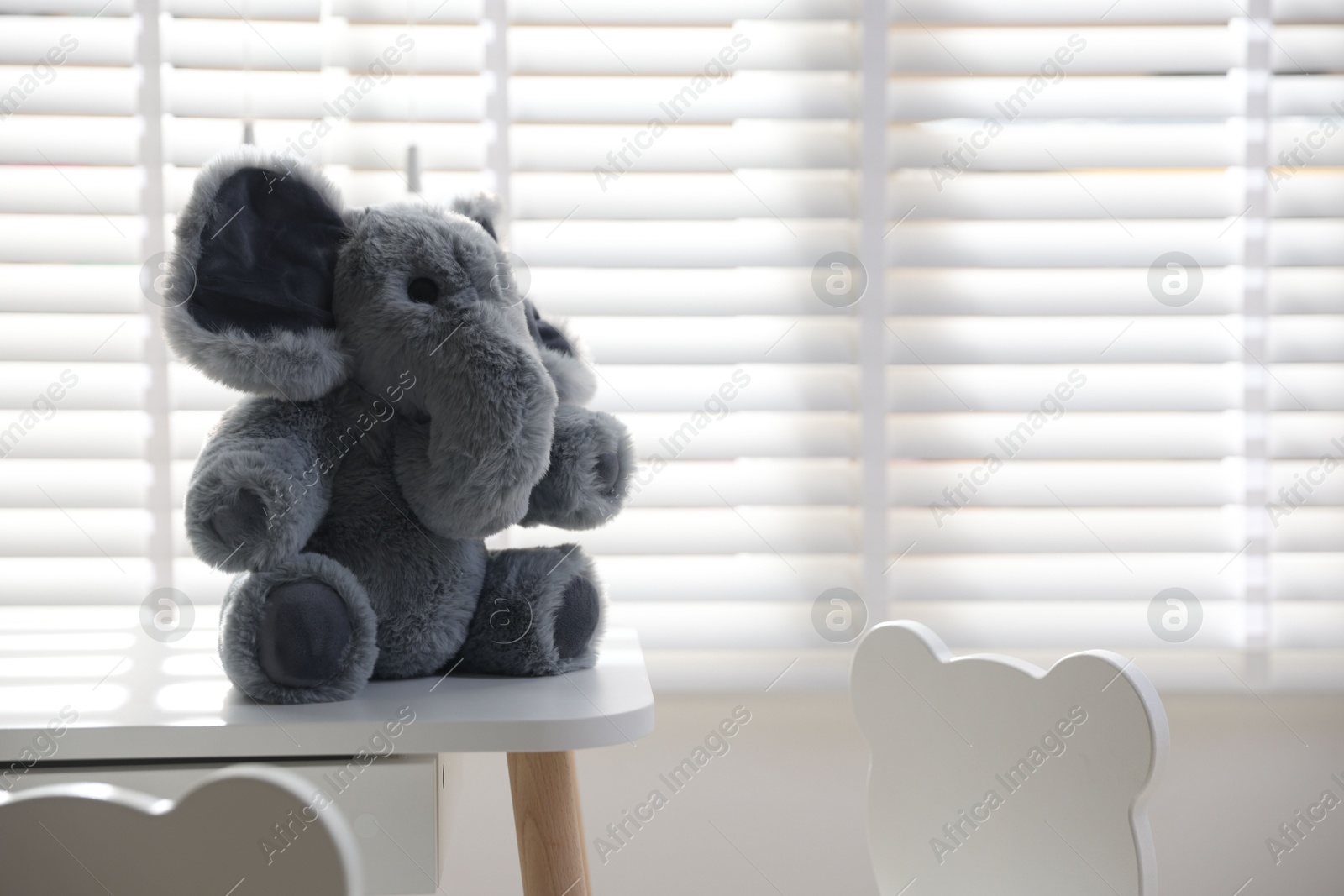 Photo of Cute elephant on table in child's room. Space for text