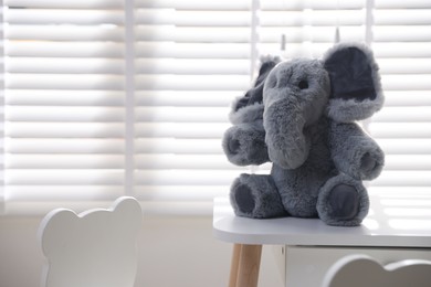 Cute elephant on table in child's room. Space for text