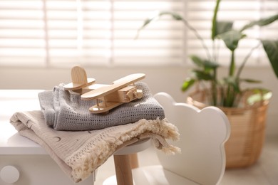 Photo of Toy plane and blankets on table in child's room. Space for text