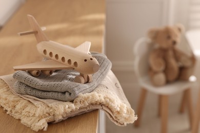 Photo of Toy plane and blankets on chest of drawers in child's room, closeup