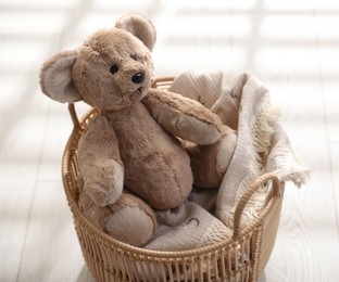 Cute teddy bear in basket on floor, closeup