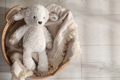 Photo of Cute toy sheep in basket on floor, top view. Space for text