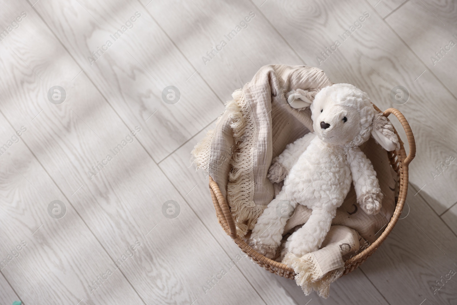 Photo of Cute toy sheep in basket on floor, top view. Space for text