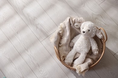 Photo of Cute toy sheep in basket on floor, top view. Space for text