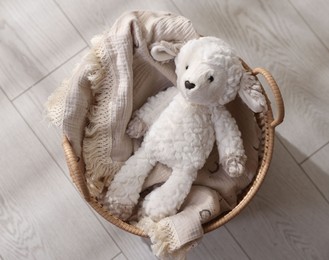 Photo of Cute toy sheep in basket on floor, top view