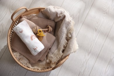 Photo of Different baby accessories in basket on floor, top view. Space for text