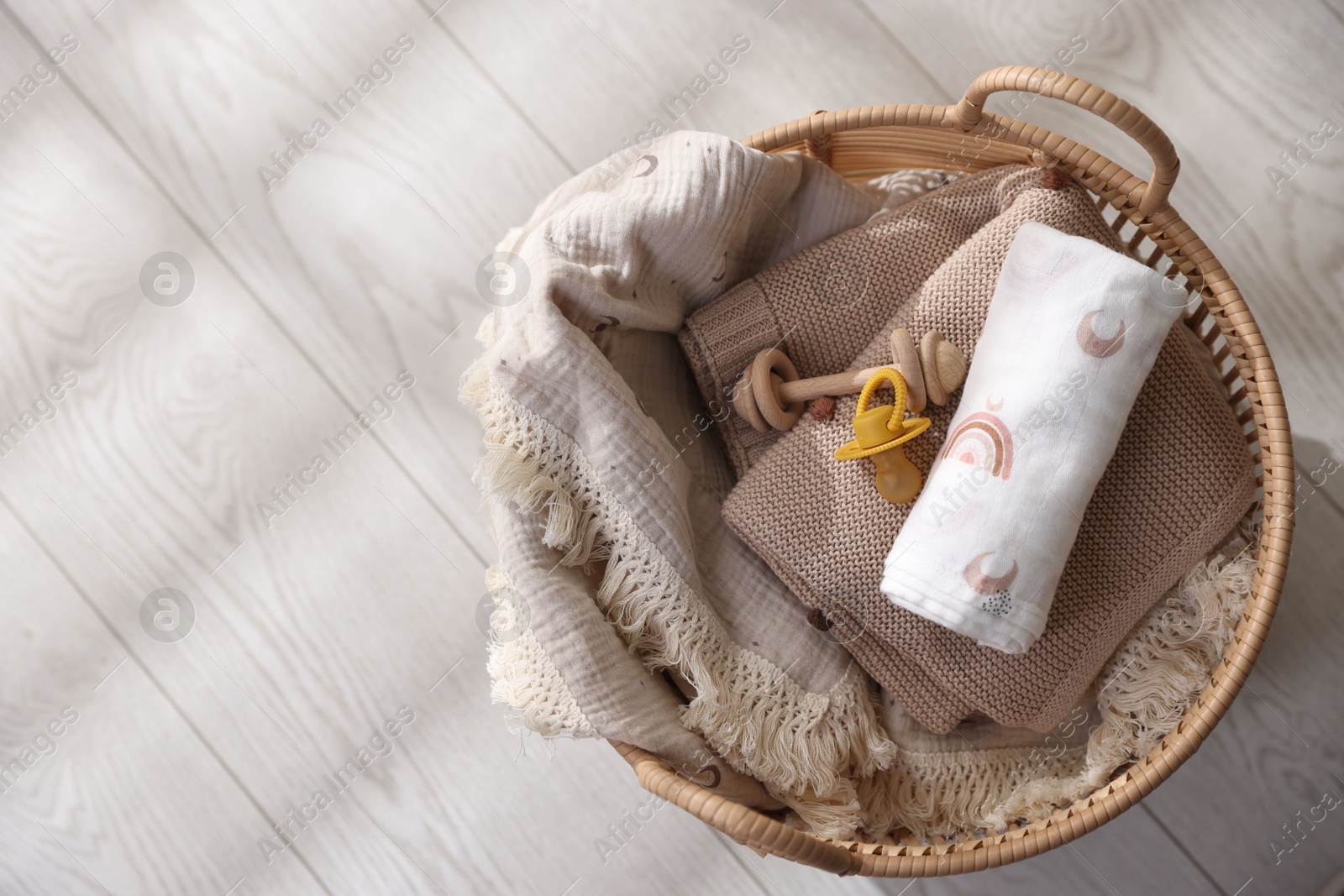 Photo of Different baby accessories in basket on floor, top view. Space for text