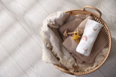 Photo of Different baby accessories in basket on floor, top view. Space for text