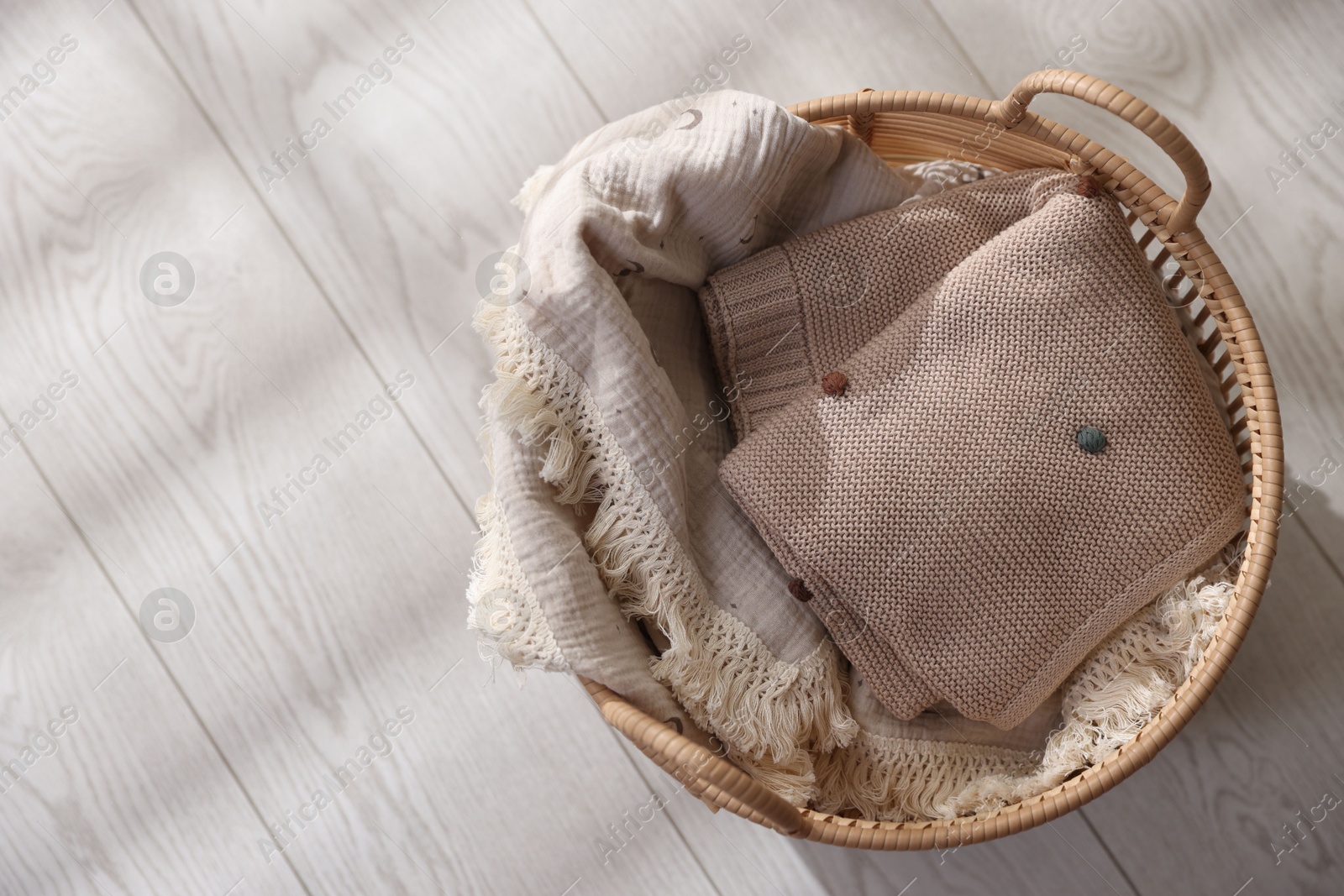 Photo of Baby blankets in basket on floor, top view. Space for text