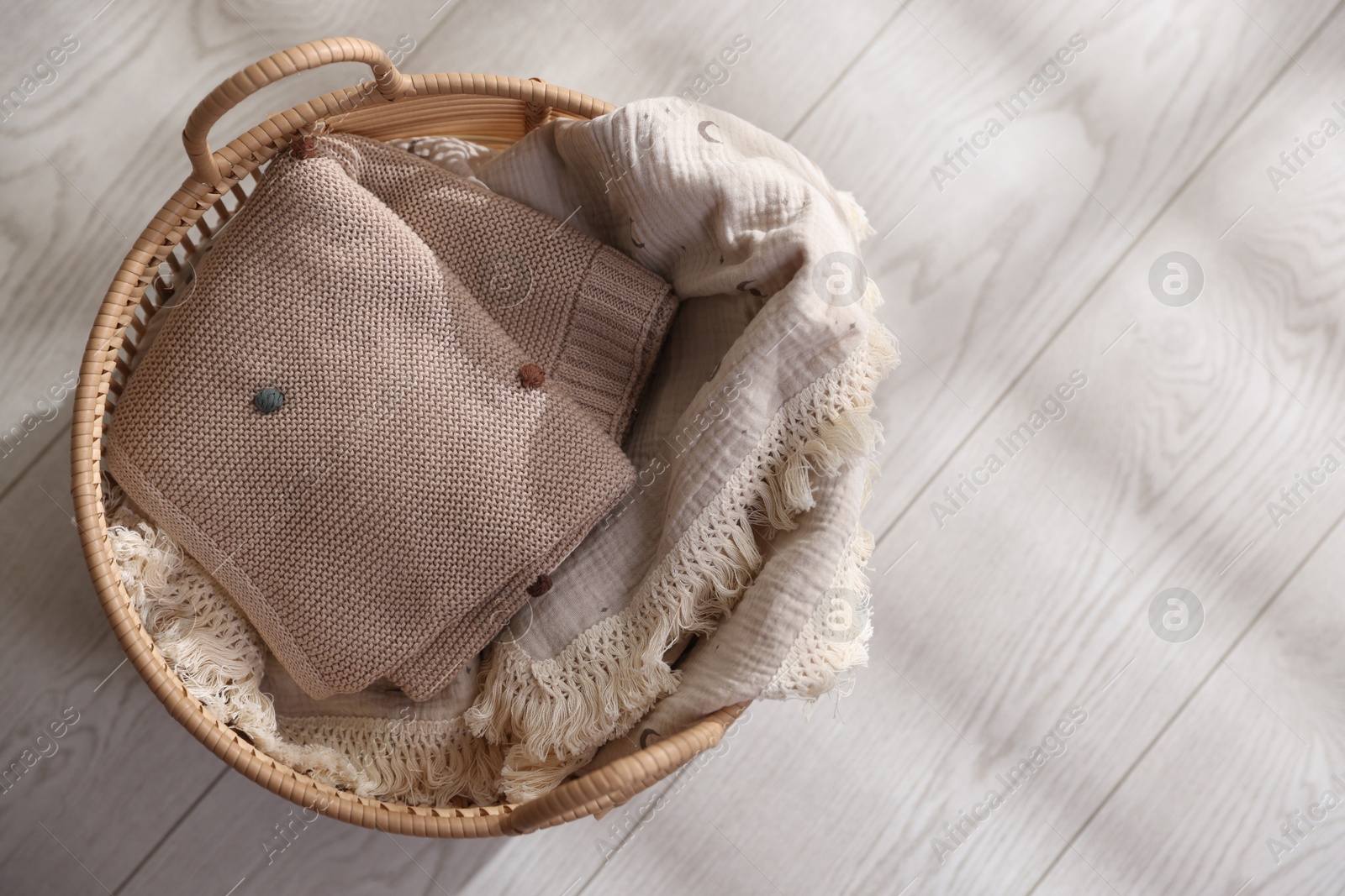 Photo of Baby blankets in basket on floor, top view. Space for text