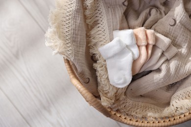 Photo of Different baby accessories in basket on floor, top view. Space for text