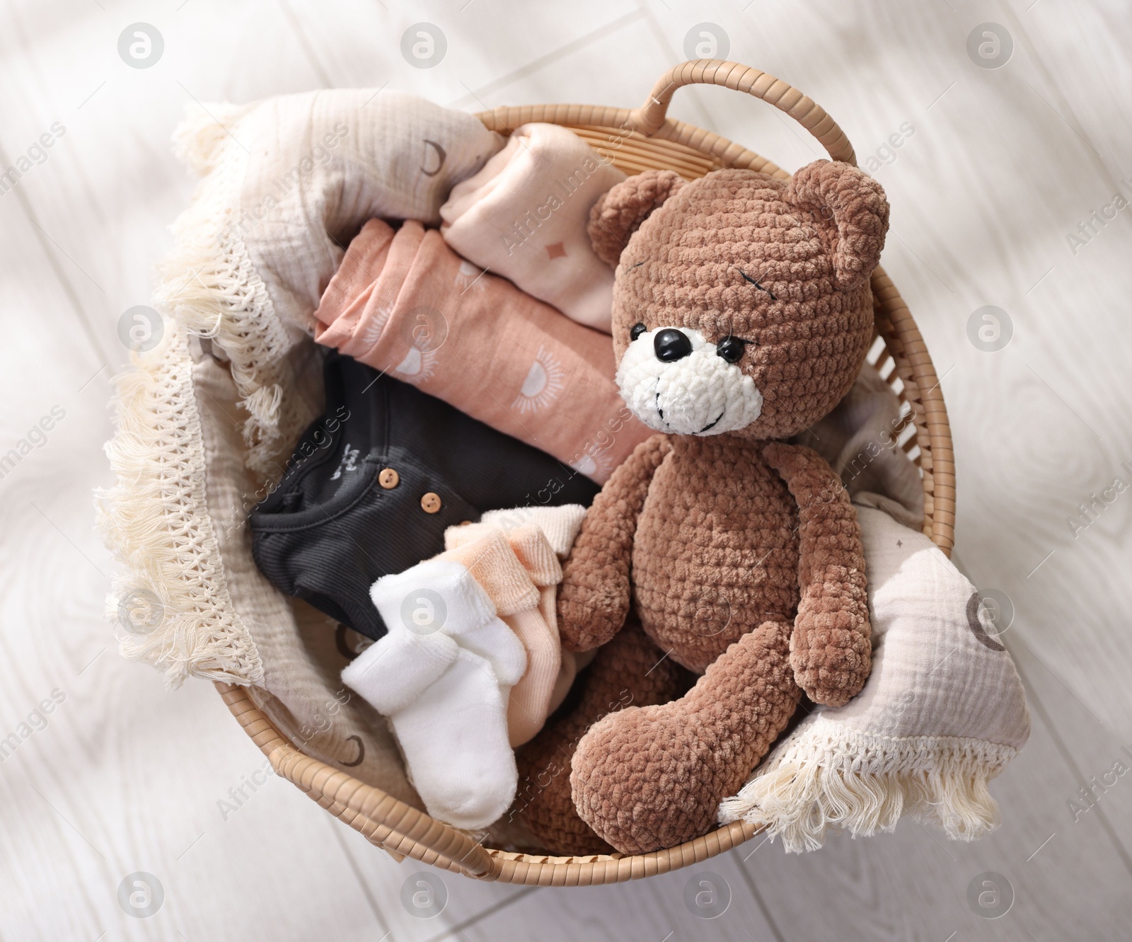 Photo of Different baby accessories in basket on floor, top view