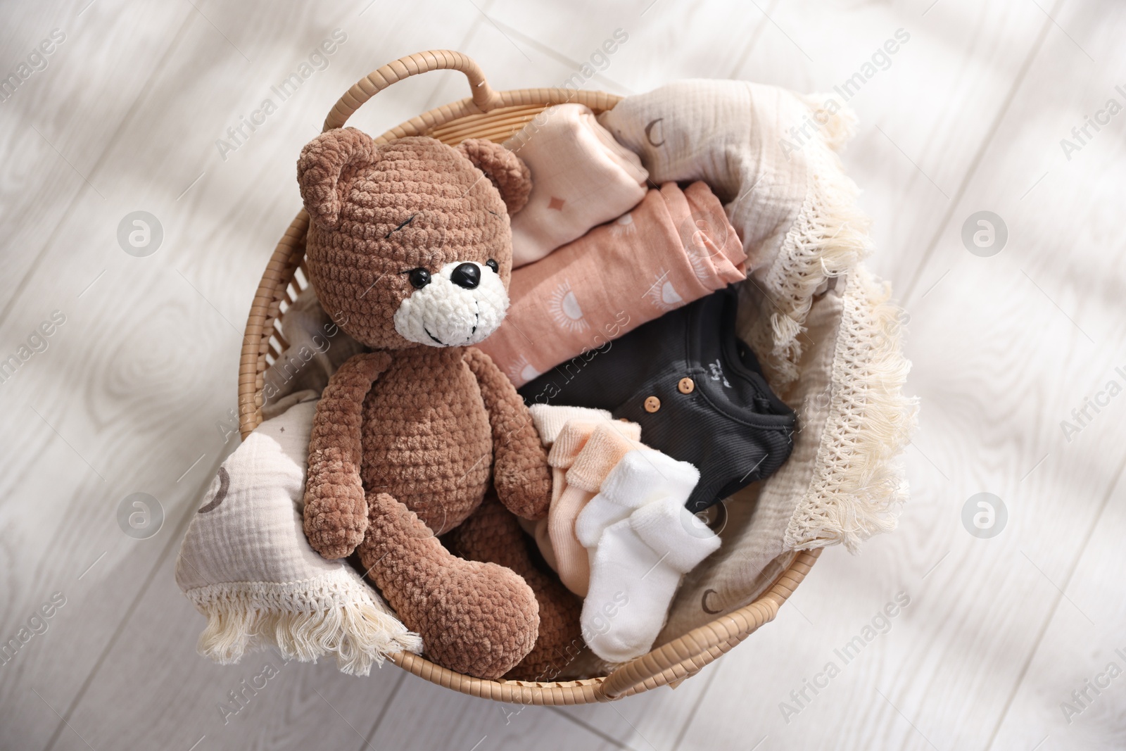 Photo of Different baby accessories in basket on floor, top view