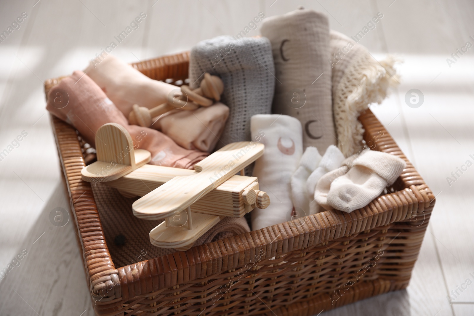 Photo of Different baby accessories in basket on floor, closeup