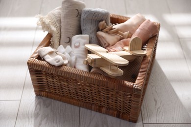 Photo of Different baby accessories in basket on floor, closeup