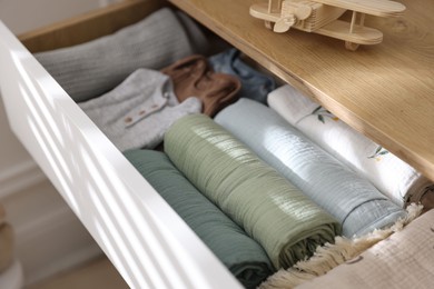 Different baby clothes and swaddles in drawer indoors, closeup