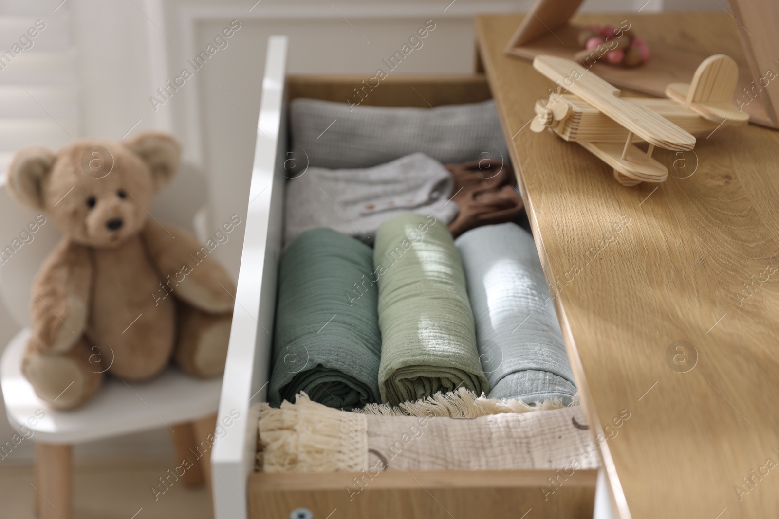 Photo of Different baby clothes and swaddles in drawer indoors, closeup