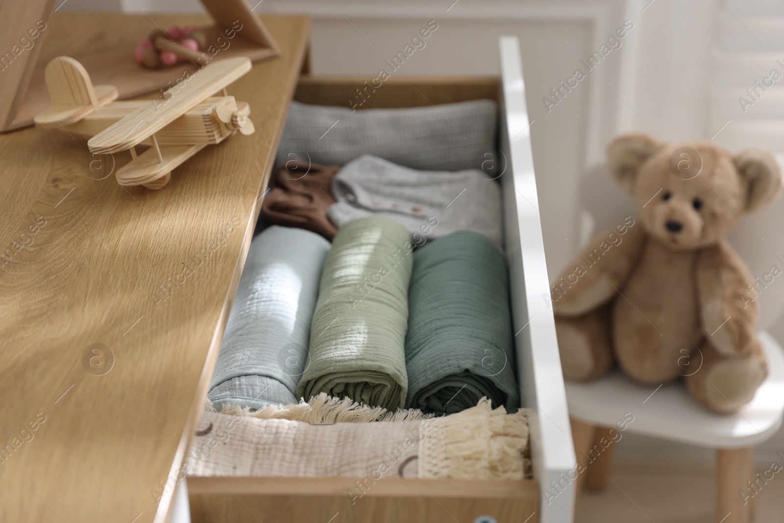 Photo of Different baby clothes and swaddles in drawer indoors, closeup