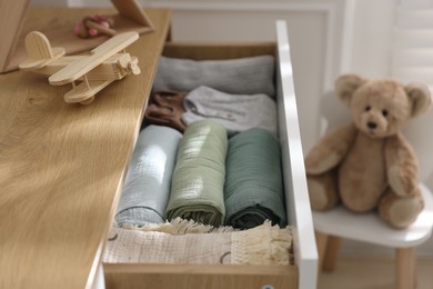 Different baby clothes and swaddles in drawer indoors, closeup