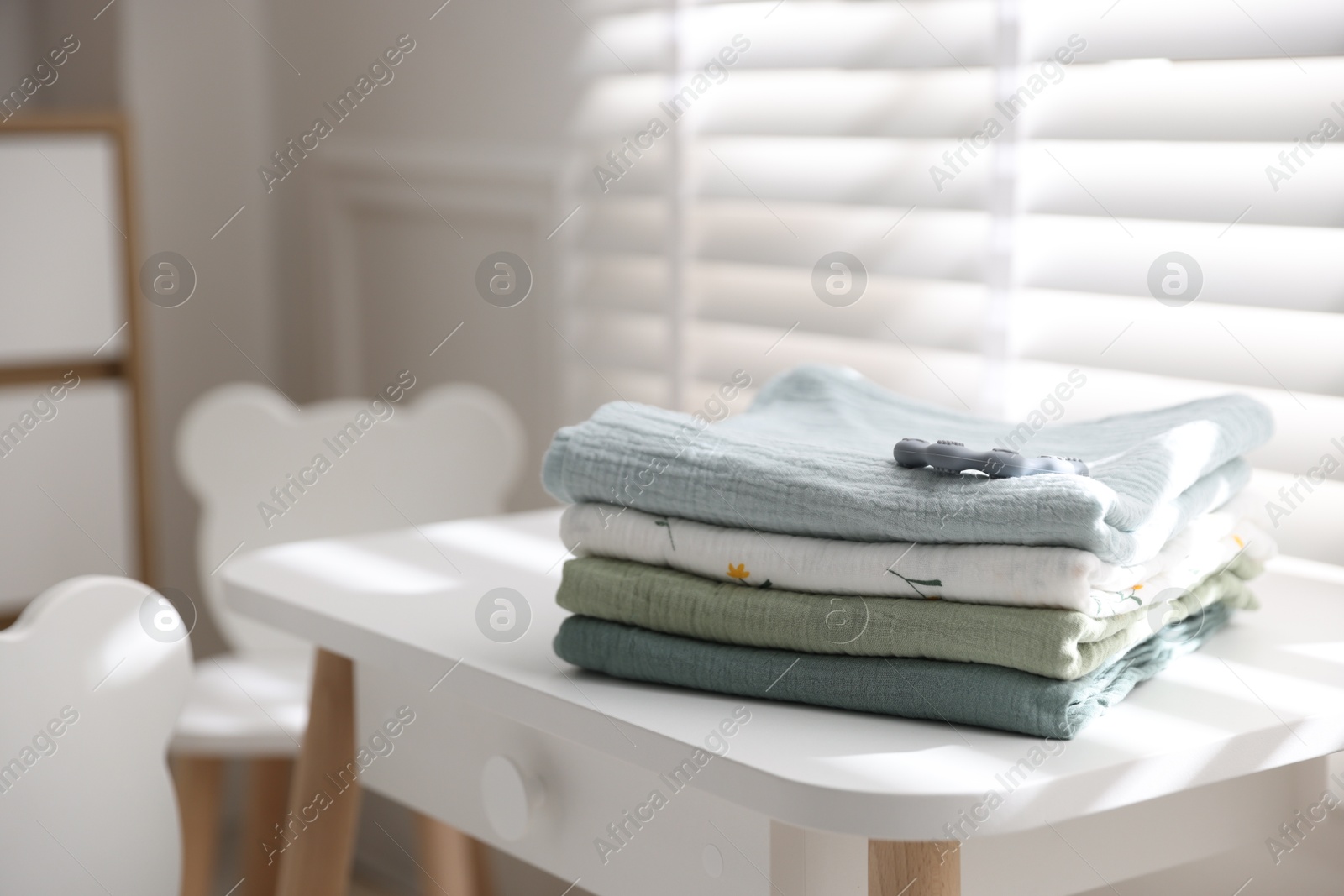 Photo of Baby swaddles and teether on table indoors. Space for text